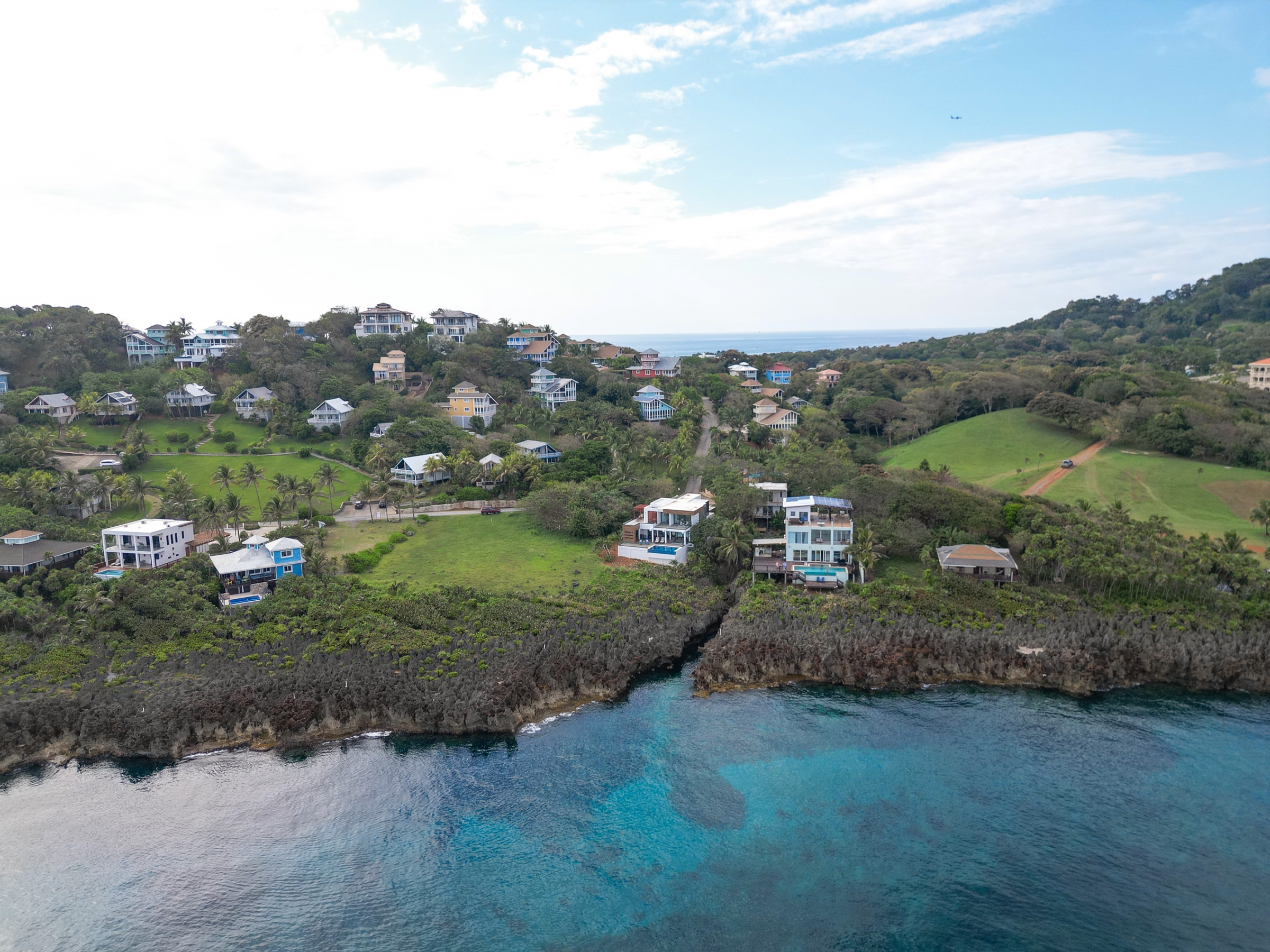 Aerial view of Lighthouse Estates homes above Roatan's rocky coastline and turquoise water